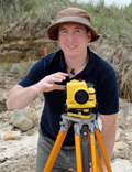 Picture of  man on the beach using siting tool on a tripod.