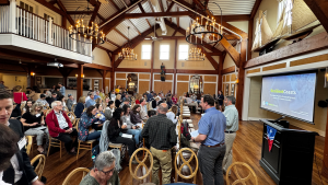 About 70 attendees gather in the meeting room at the Green Harbor Yacht Club  at the start of the 2025 Nantucket Coastal Conference.